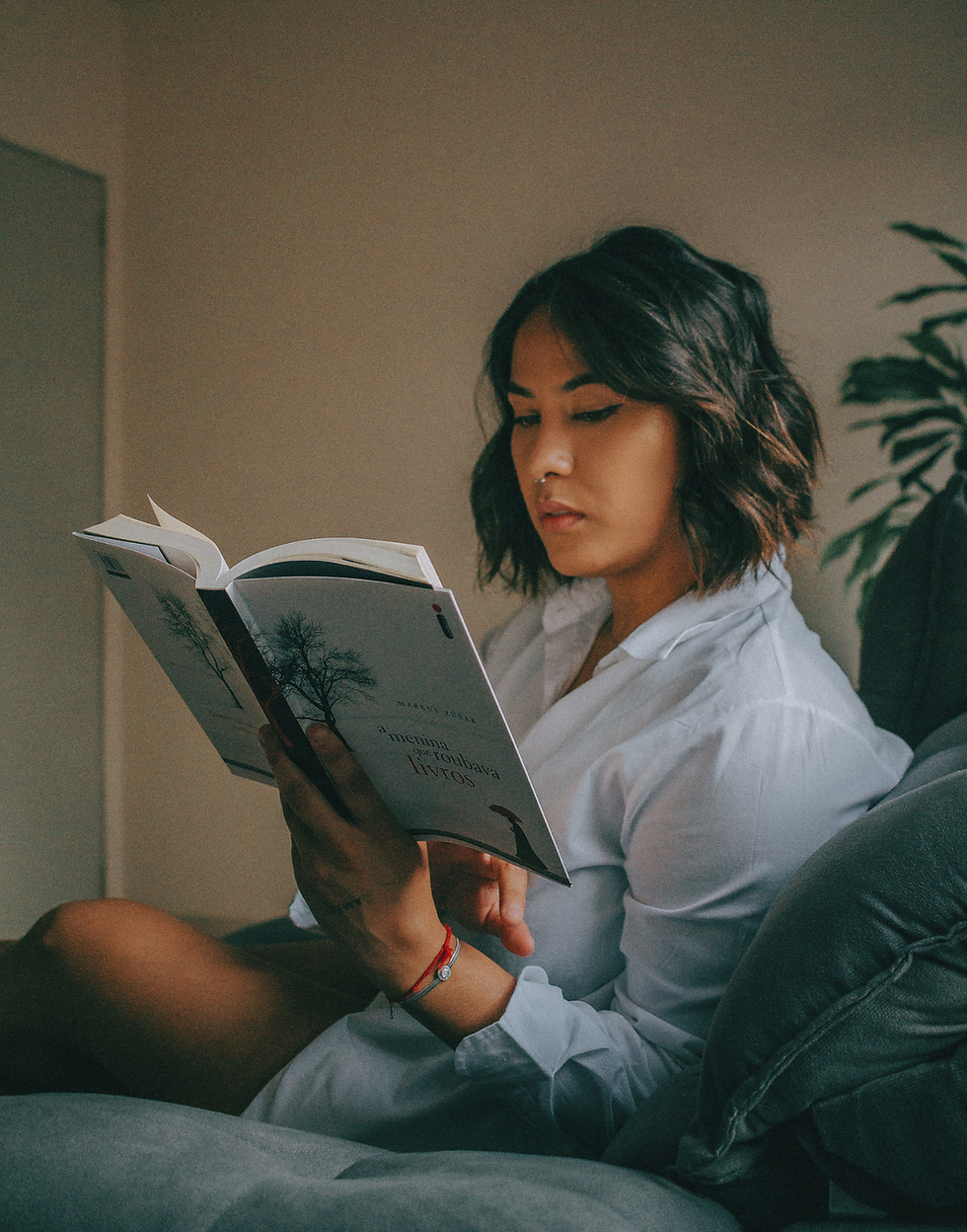 Woman sitting comfortably indoors reading a book during her digital detox routine, symbolizing mindfulness, calm focus, and protecting mental energy from screen fatigue.