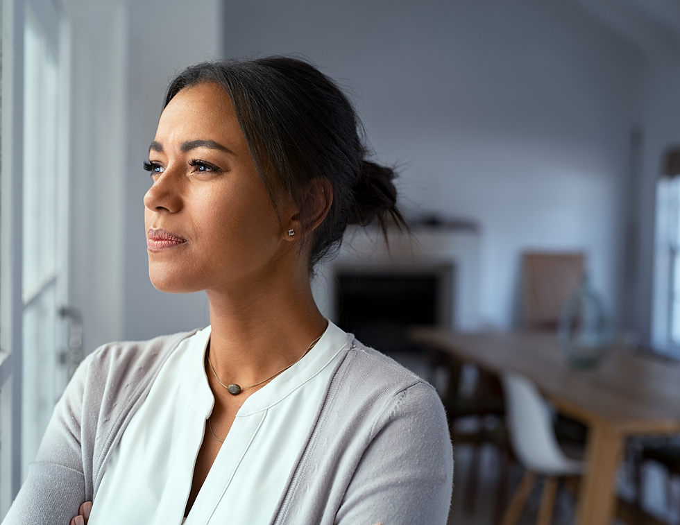 Woman sitting by a window with a journal, practicing quiet reflection as part of a calm daily routine at home.