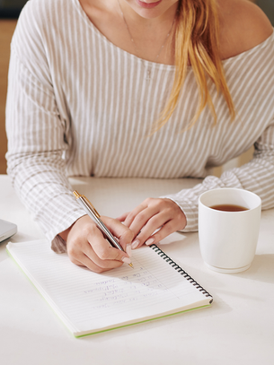 Self improvement for women writing in a notebook with coffee, building daily habits for personal growth and a balanced life.