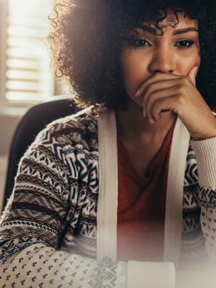 Thoughtful woman at a desk pausing to reflect, representing decision-making skills and how to make better decisions without second-guessing yourself.