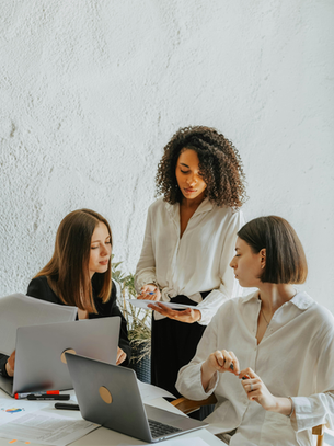 A group of women collaborating in a modern office, representing workplace wellness, teamwork, emotional balance at work, and the importance of meaningful connection for women navigating work-life balance.
