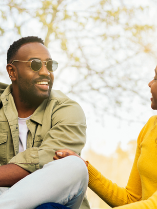 A man and woman sitting outdoors having a warm, relaxed conversation — symbolizing open, healthy communication and emotional connection.