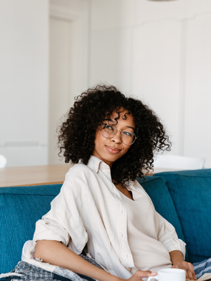 Woman relaxing on a couch during a quiet moment of self-reflection with coffee.