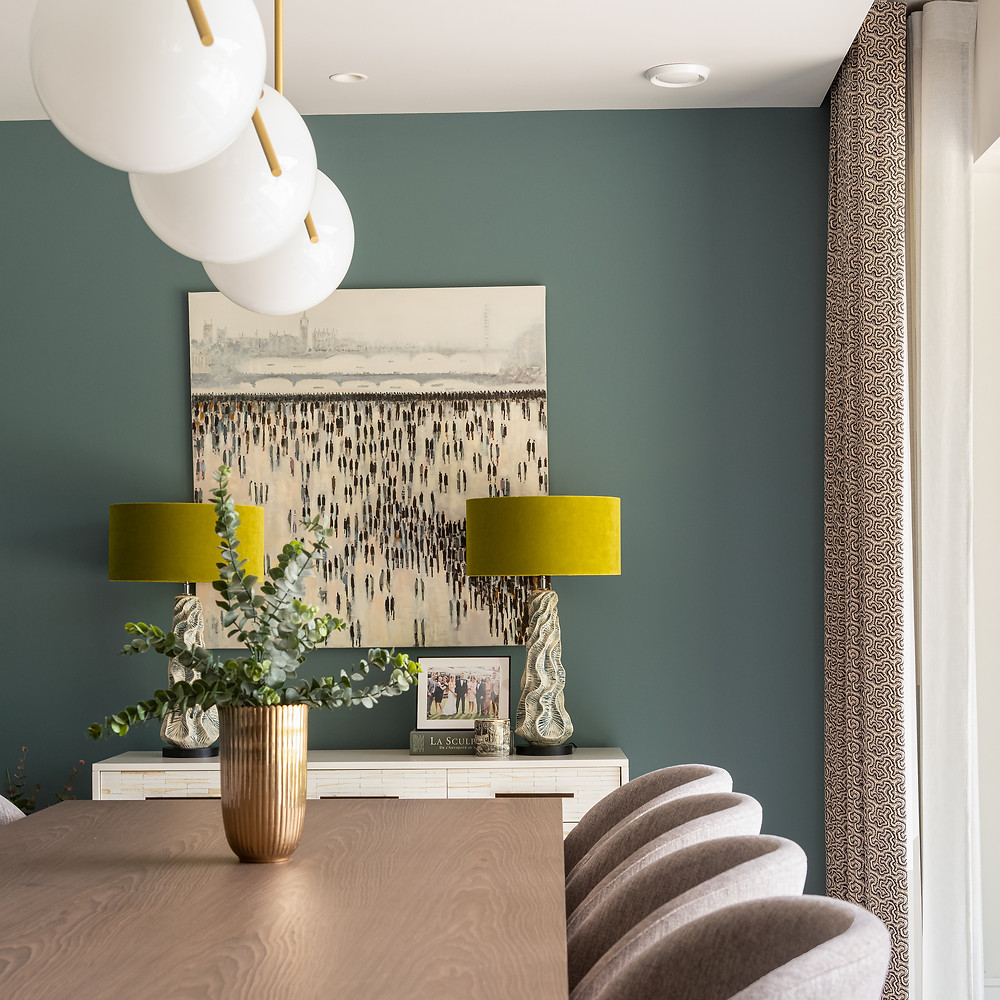Pookie light over a dining table. Comfortable dining chairs. Oval room blue walls. Neutral graphic pencil pleat curtains.