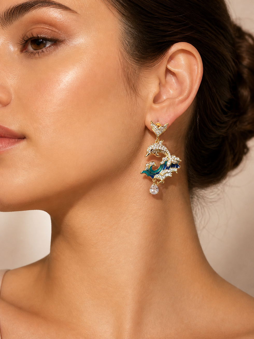 Model wearing Ocean Whisper Dolphin Earrings featuring crystal-studded dolphin motifs, blue enamel ocean waves