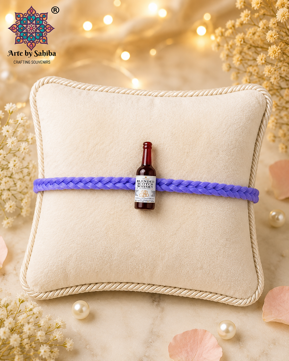 2-in-1 miniature Blended Scotch Whisky bottle Rakhi with a white and gold label and a purple braided thread on a soft cream c