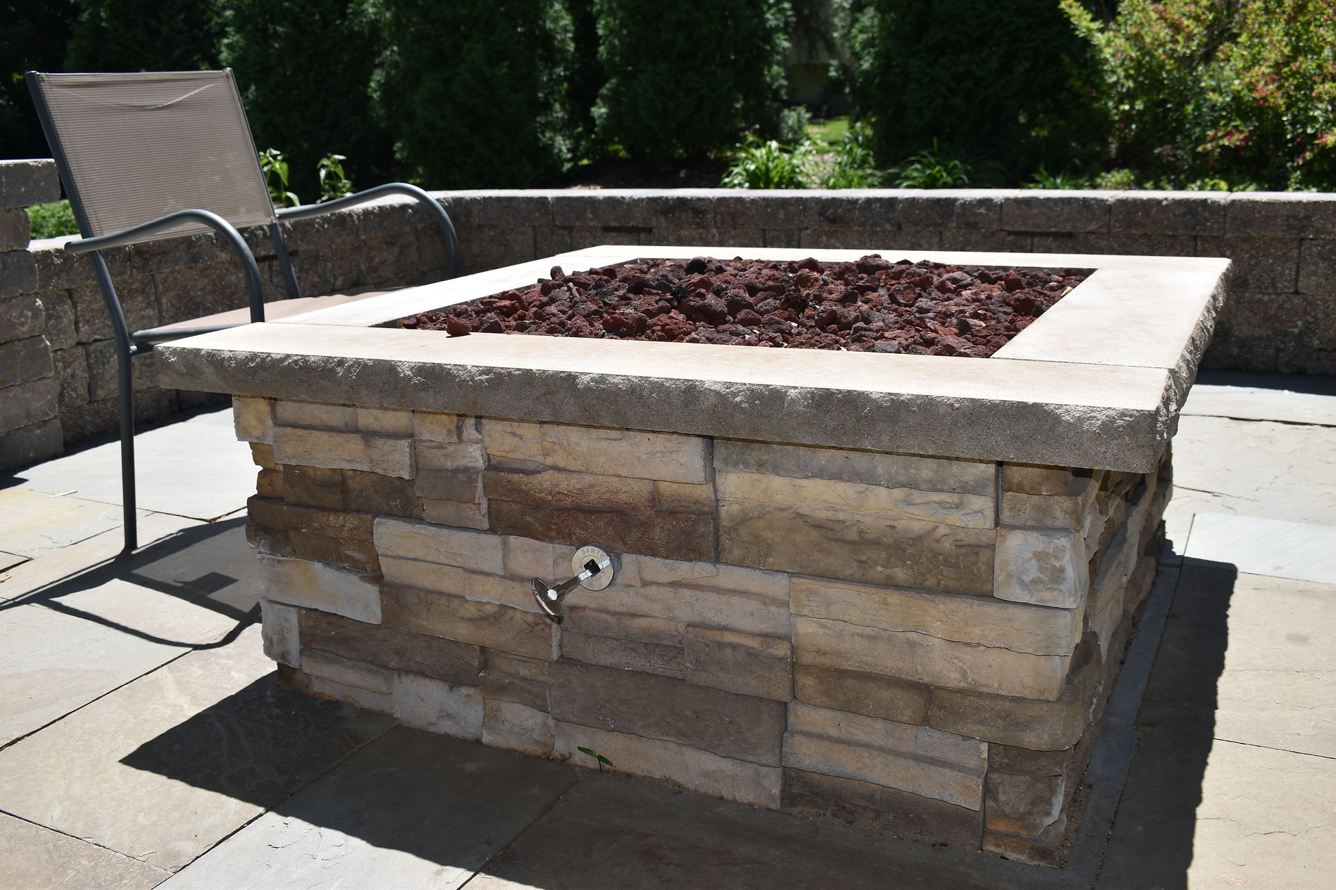Modern custom stone fire pit in a Mendota Heights, MN backyard featuring a New York bluestone patio
