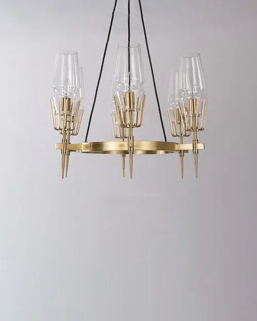 Thumbnail: Elegant golden chandelier with glass shades hanging against a white wall.