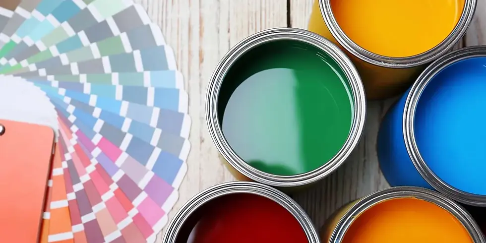Open paint cans in yellow, blue, green, and red on wooden surface. Fan of color swatches beside them, creating a creative mood.