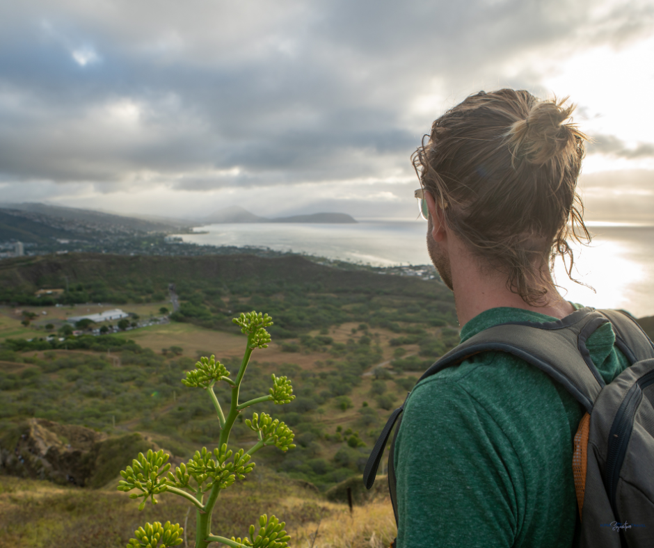 Man on mountain top looking down at water