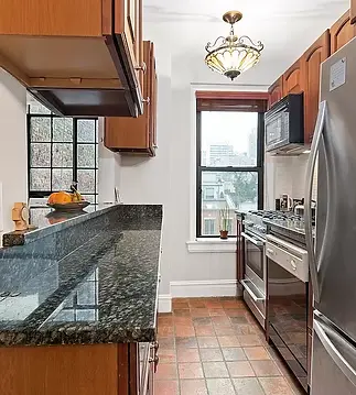 Before picture of very narrow galley kitchen with dark wood upper and lower cabinets, and green granite breakfast bar