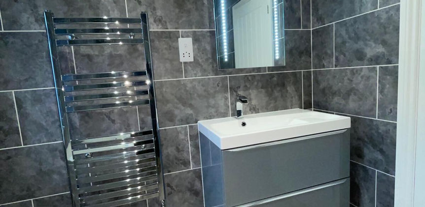 Grey sink cabinet with mirror and heated towel rail