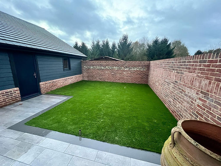 Freshly laid turf with grey paving around the edges