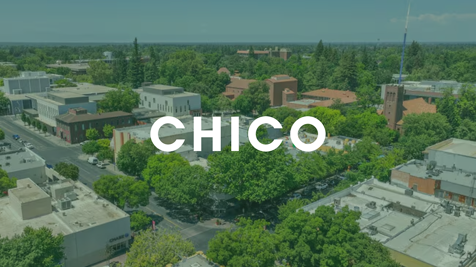 Aerial view of a cityscape with lush green trees, buildings with red roofs, and "CHICO" text overlaid. Clear sky in the background.
