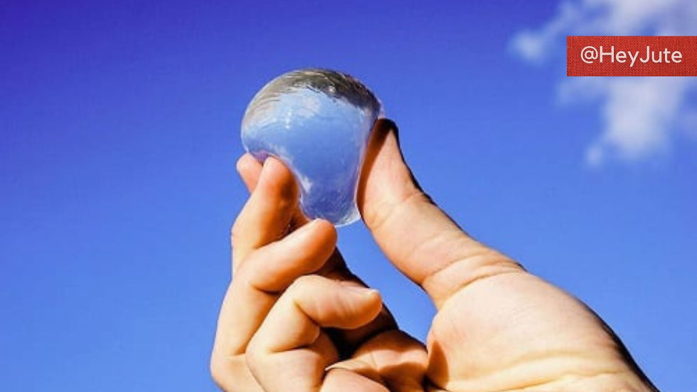 a hand holding up an edible plastic bubble of water