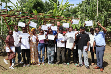 Cooking trainees holding up certificates after completing culinary arts training.