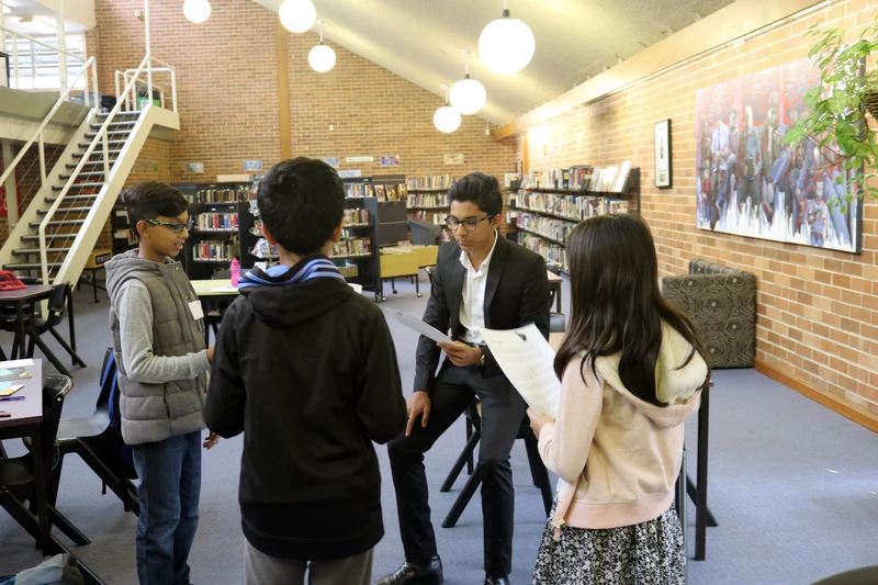 Kailash teaching three primary school kids at an in-person Leadership Through Public Speaking class