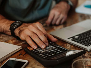 Homem fazendo cálculos em uma calculadora de mesa portátil em seu escritório