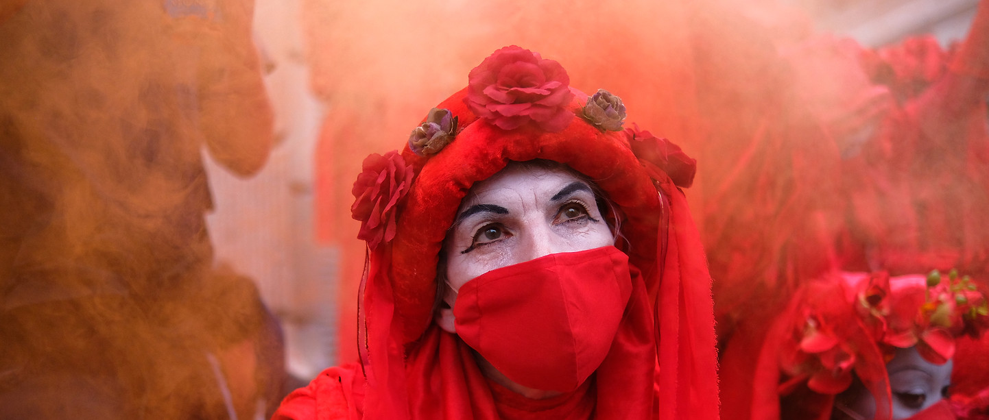 Red rebels surrounded by red flare smoke at an Extinction Rebellion protest