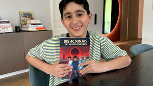 Malik Ekinci mit seinem Buch in der Hand am Esstisch.