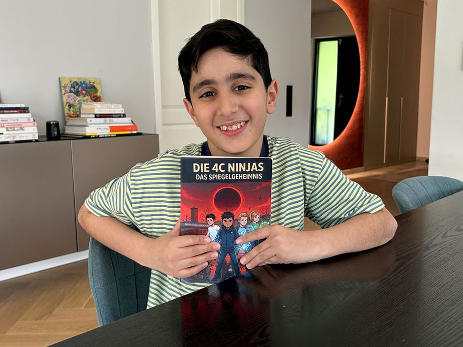 Malik Ekinci mit seinem Buch in der Hand am Esstisch.