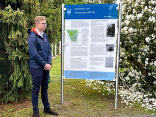 Ein Schüler vor einer Gedenktafel auf einem Friedhof.