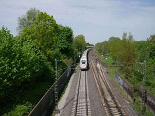 ICE in voller Fahrt auf einem Gleis mit viel Grün drumherum.