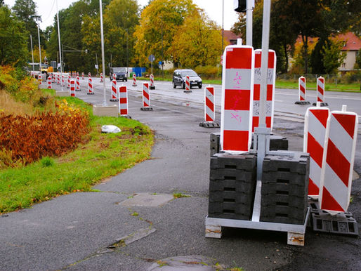 Baustelle an Straße und Radweg mit Autos und Absperrungen.
