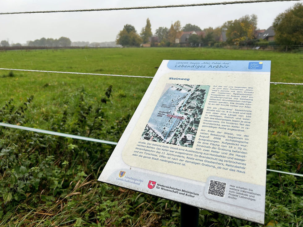 Schild am Apfelweg in Altencelle, dahinter eine große Wiese.