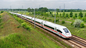 ICE-Zug auf einer Bahnstrecke durch viel Grün mit Strommasten.