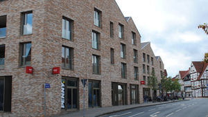 Wohnblock Village in Celle mit Supermarkt und Bäumen.