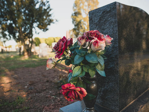 Grabstein von hinten mit einem Strauß Rosen.