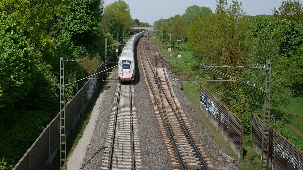 ICE in voller Fahrt auf einem Gleis mit viel Grün drumherum.