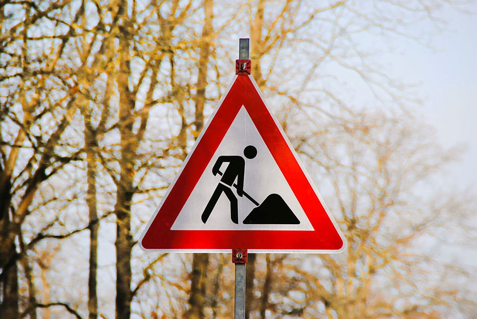 Baustellenschild vor unscharfem herbstlichen Hintergrund.
