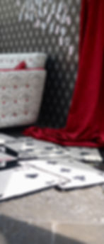 A stylish red and black room featuring vibrant red curtains, rug with a playing card design, and a matching sofa.