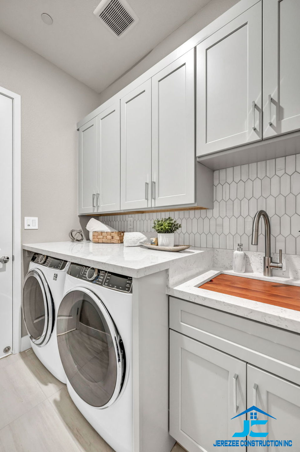 White laundry room remodel with washer, dryer, and sink.