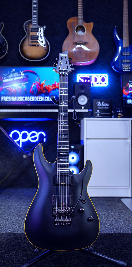 Schecter Guitar with guitars in background at Fresh Music Aberdeen