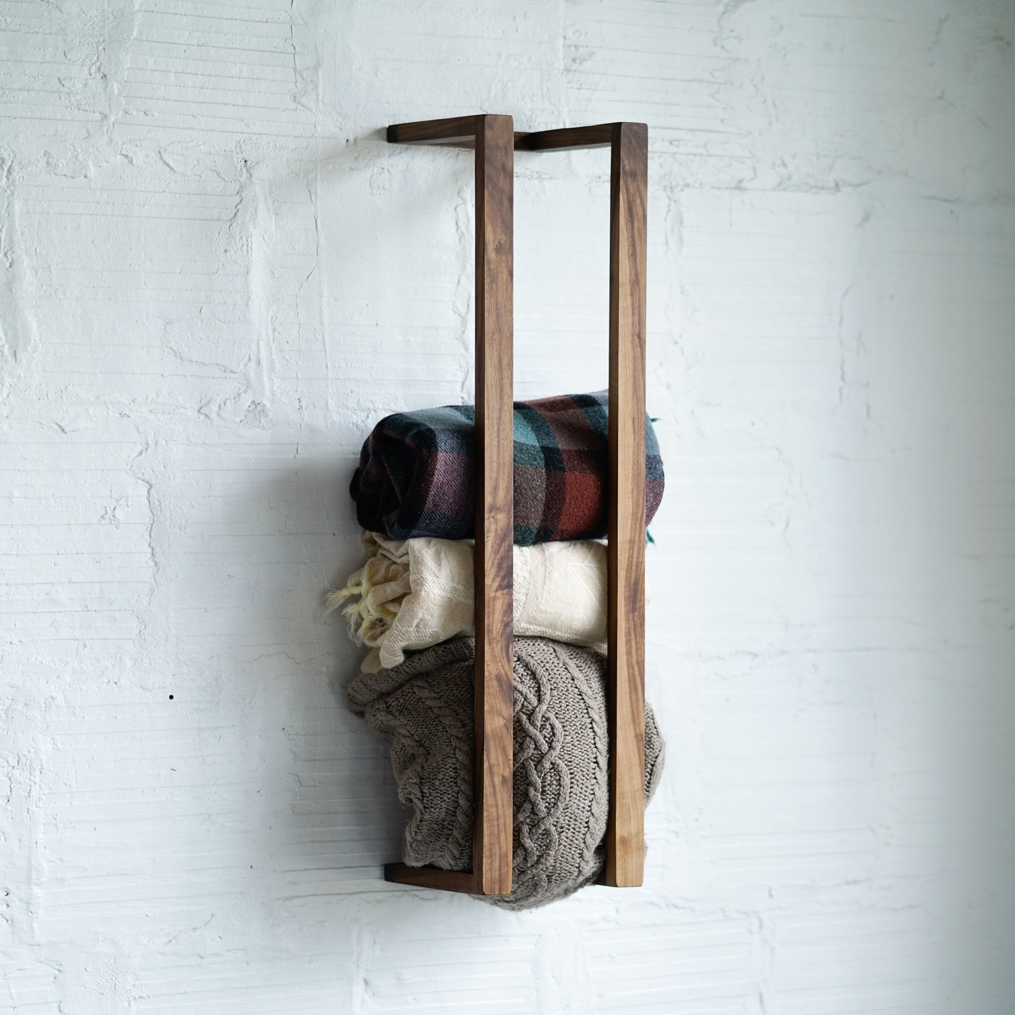 Blankets on a rustic wooden wall rack.
