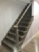 Finished curved wooden staircase with black iron balusters and hardwood stair treads.
