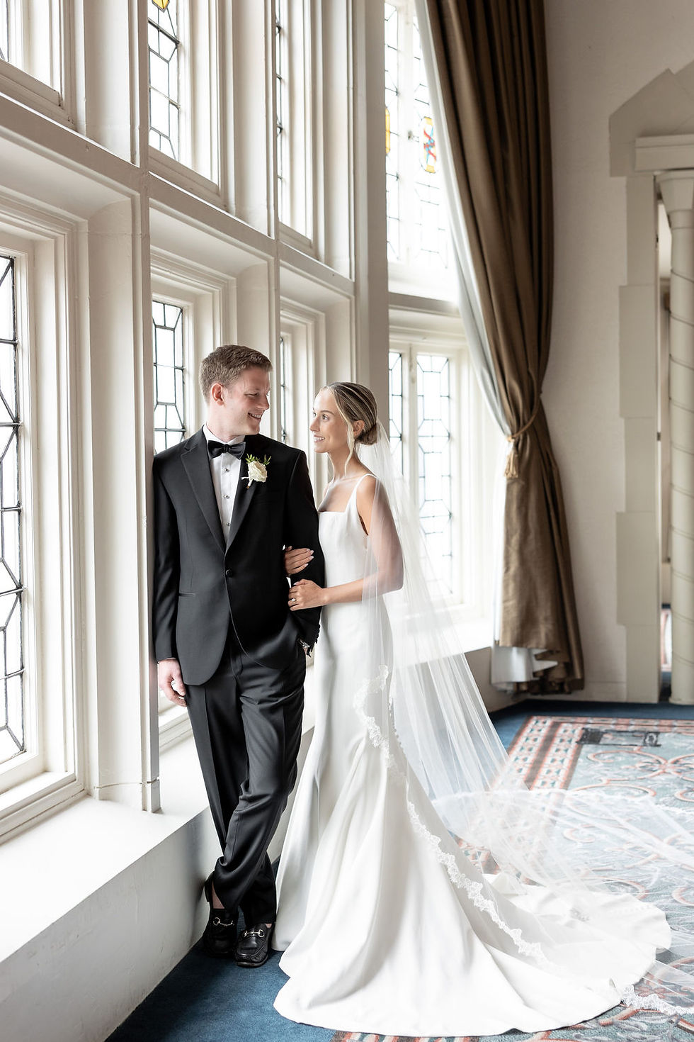 bride and groom looking at eachother by a window