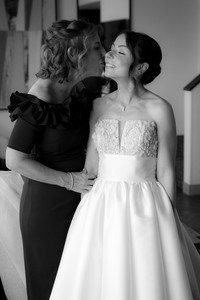 mother of bride kissing bride on cheek in wedding gown