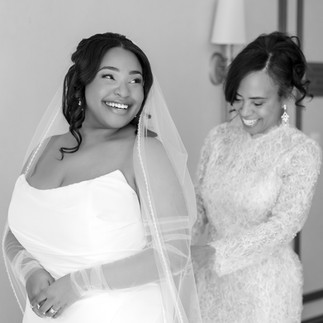 mom doing the back of her daughters wedding dress both smiling and happy