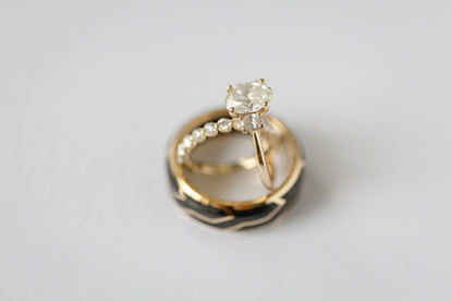 close up shot of brides rings and grooms wedding band that is black engraved