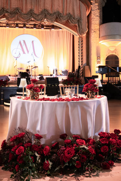 sweetheart table at wedding with red florals surrounding table