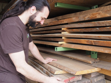Le menuisier Guillaume Duret en admiration devant des planches de hêtre blanc