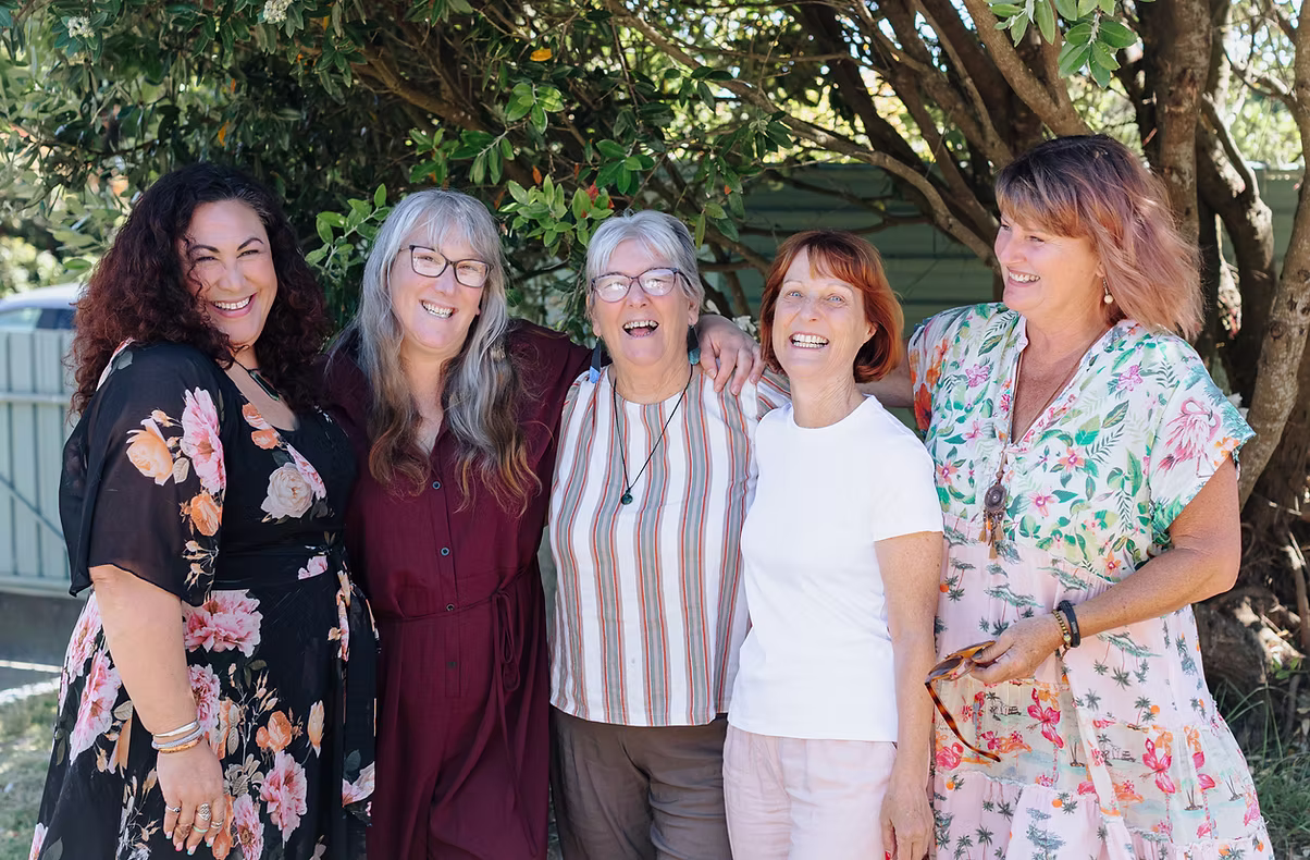 Group of five women, all happy, standing outside under the trees