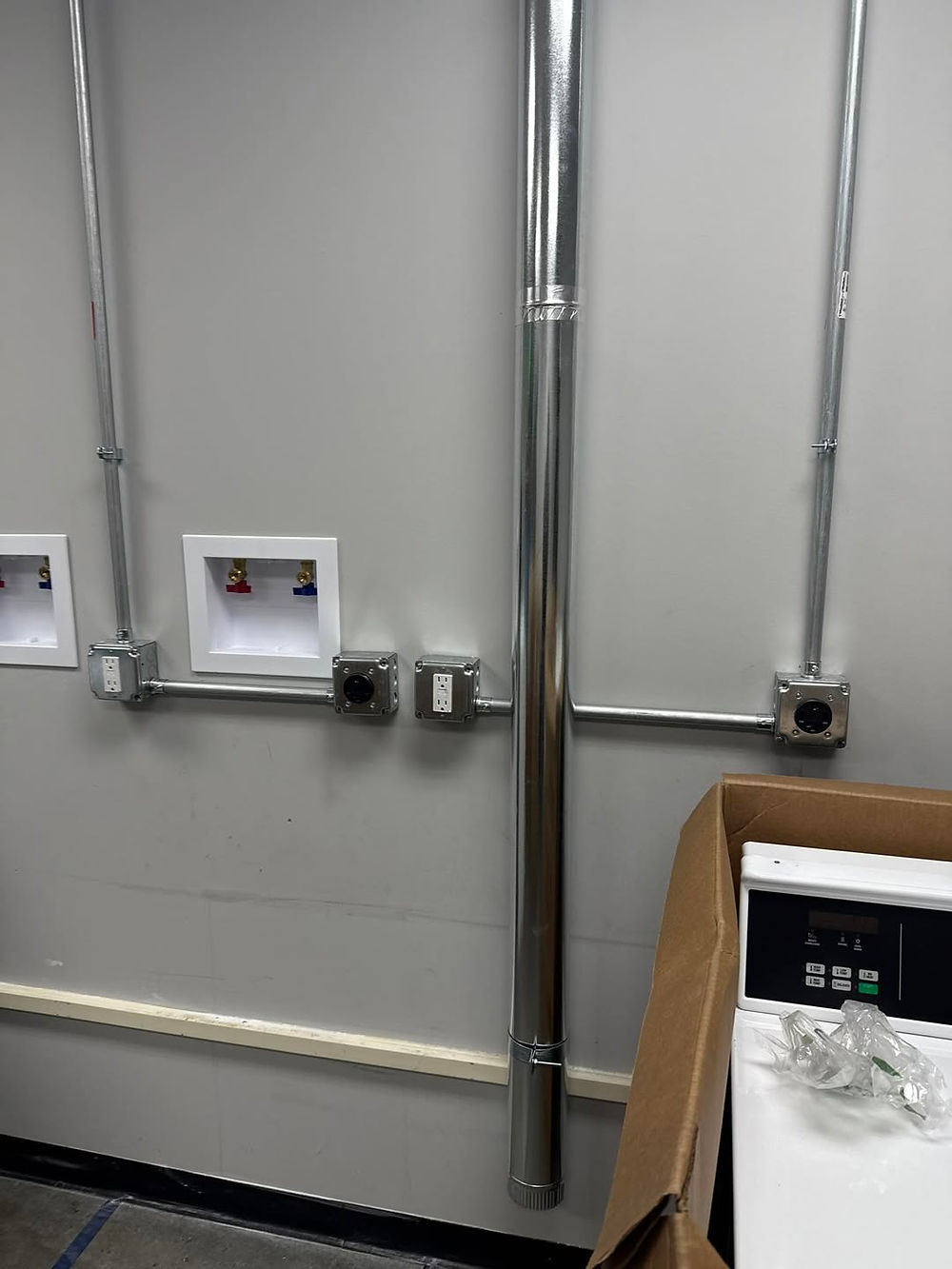 Wall showing laundry hookups, electrical outlets, and ductwork