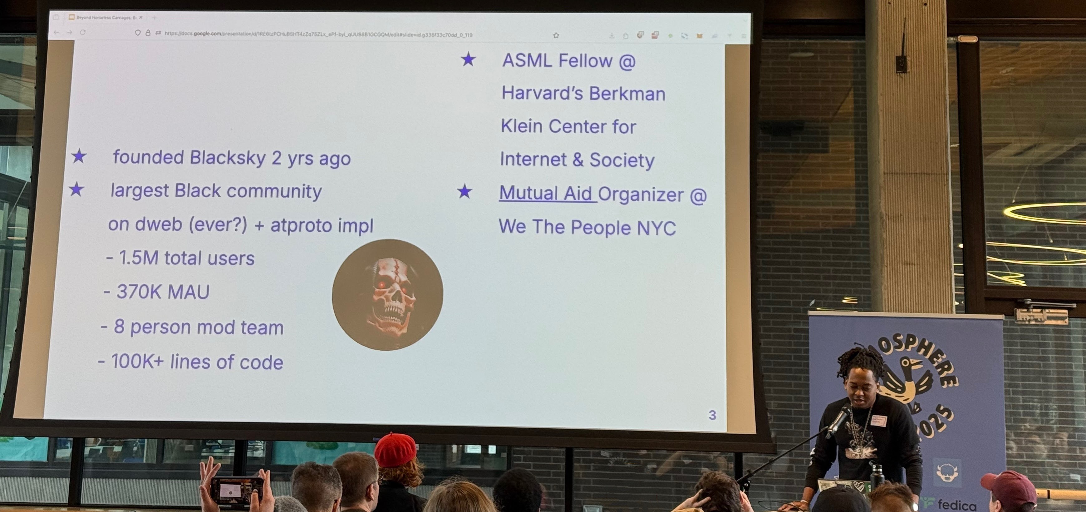 a photo of BlackSky founder Rudy Fraser speaking at the Atmosphere conference in Seattle, in front of a presentation with information about him