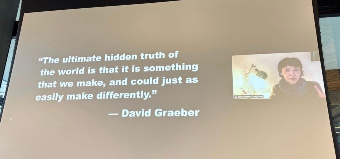 a photo of Erin Kissane speaking remotely at the Atmosphere conference, seen on a large display next to a quote by David Graeber.