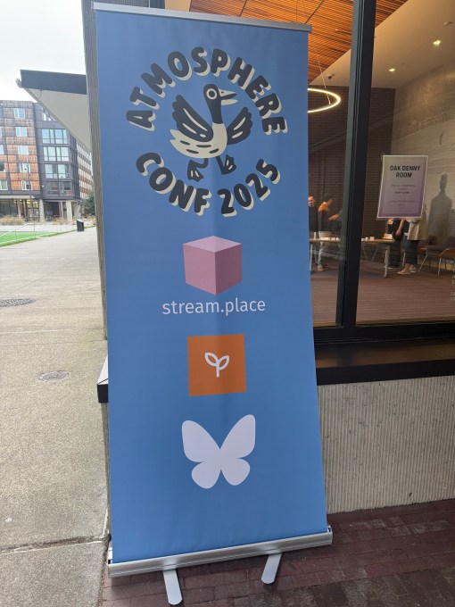 a blue vertical banner ad outside the Atmosphere Conf 2025 in Seattle